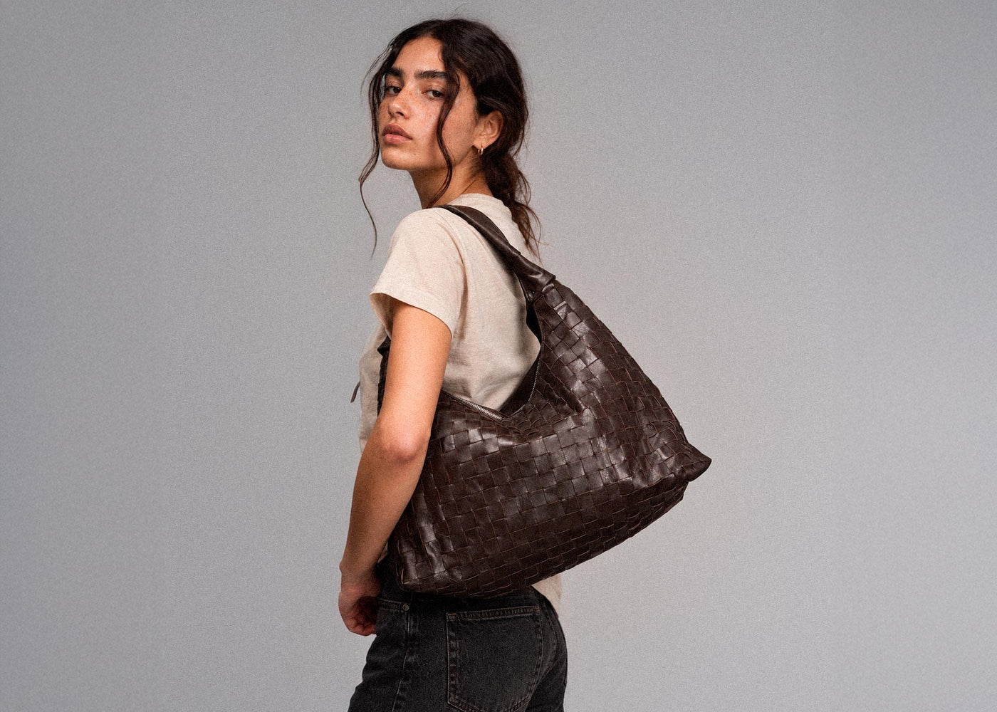 Model wearing a woven brown leather bag from the Secret Sale campaign